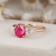 a pink diamond ring sitting on top of a white box with flowers in the background