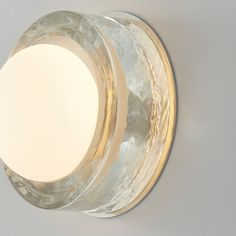 a light that is on the wall above a glass bowl with a white disc in it