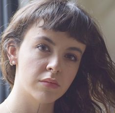 a close up of a person wearing a necklace and nose piercing on her left ear