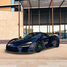 a blue sports car is parked in front of a building with large windows and doors