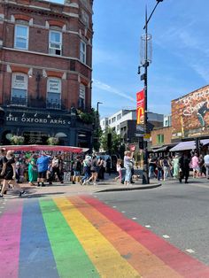 a rainbow painted crosswalk in the middle of a city street with people walking on it