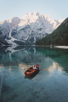 a small boat floating on top of a lake surrounded by mountains