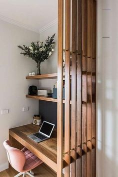 a desk with a laptop on top of it in front of a wooden shelf filled with books