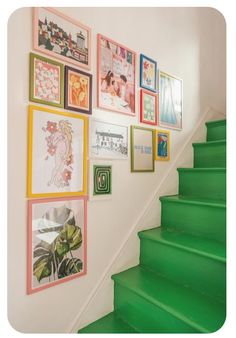 a staircase with green steps and pictures on the wall above it, along with other framed artwork