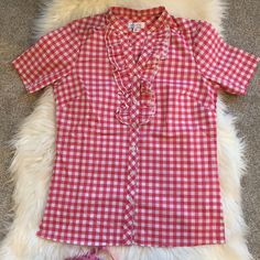 a red and white checkered shirt laying on top of a furry rug next to a pair of pink shoes