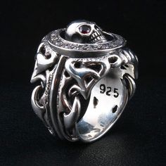 Tribal Garnet Skull 925 Sterling Silver Gothic Ring  Ring width : 7/8" x1" inch  Ring weight : 28 grams   Material:.925 sterling silver   Made of solid sterling silver and featuring a unique design engravings of a skull, this is a one of a kind ring. The center piece skull features two blood red garnet gemstone eyes. Solid and masculine in design, this ring is a must-have for your biker jewelry accessory collection.  It will hold up to years of wear and tear and will handle any road trip you hea White Gold Round Skull Ring Stamped 925, Sterling Silver Skull Ring Hallmarked, Sterling Silver Skull Ring Stamped 925, Engraved White Gold Skull Ring In Sterling Silver, Sterling Silver Hallmarked Skull Ring Collectible, Collectible Sterling Silver Skull Ring With Polished Finish, Silver Gothic Skull Ring, Gothic Silver Sterling Silver Skull Ring, Unique Silver Skull Rings