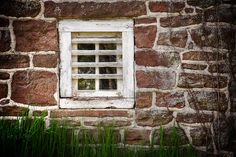 an old brick building with a window and grass