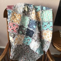 a chair with a quilt on it sitting in front of a wall and a table