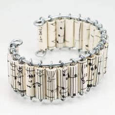 a bracelet made out of sheet music notes on white paper with metal links and clasps