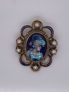 "Vintage 14k yellow gold painted portrait of woman brooch with pearls. The center is porcelain made in France and the paint has intricate details including iridescence on the hat and bodice. The portrait is surrounded by seed pearl beads and 6 larger pearls on the N/S/E/W. A blue enamel border matches the color of the porcelain. The brooch measures 1.5\" long and 1.25\" wide and there is a hidden bail that swings up so that it can be worn on a chain. The brooch is stamped 14K and weighs 9.83 grams." Yellow Gold Enamel Brooches, Victorian Enamel Brooches For Formal Wear, Victorian Enamel Brooches For Formal Occasions, Victorian Style Enamel Brooches For Formal Occasions, Victorian Style Enamel Pin Gift, Victorian Style Wedding Brooch Enamel Pin, Victorian Wedding Enamel Brooch Pin, Victorian Style Wedding Enamel Brooch Pin, Victorian Style Formal Enamel Brooch Pin