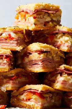 several sandwiches stacked on top of each other with meat and cheese toppings in them