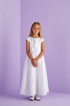 Ankle length first Holy Communion cap sleeve dress. A duchess satin dress with princess line detail, capped sleeves and front waistband with bow to centre front are complimented by the impressive scallop hem embroidery and sequin detail to the hem of the net tulle overlay skirt. Whilst at the back is a large pre tied bow with luxurious long tails completing the look and maintains a perfect bow each time you wear this dress. Fastened at the back with a hidden zip. This classic dress promotes pure Short Sleeve Dress With Fitted Bodice For Confirmation, Fitted Princess Style First Communion Dress With Short Sleeves, Princess Style Short Sleeve Dress For Confirmation, Princess Style First Communion Dress With Short Sleeves, Princess Style Short Sleeve First Communion Dress, Fitted First Communion Dress With Short Sleeves, Princess Style Short Sleeve Dress For First Communion, Satin Fitted Dress For Confirmation, Fitted Satin Dress For Confirmation