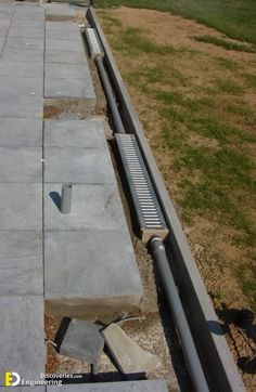 a concrete bench sitting on the side of a road next to a grass covered field