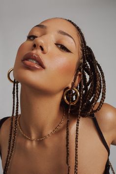 a woman with long braids and large hoop earrings on her head, looking up at the sky