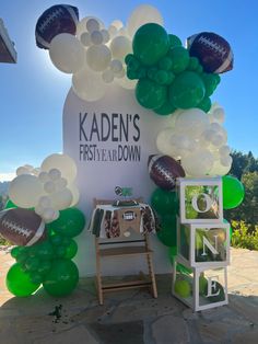 balloons and footballs are on display in front of the sign for kaden's first year down