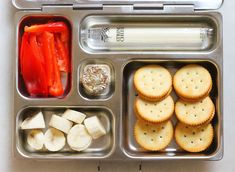 a lunch box with crackers, tomatoes and cheese