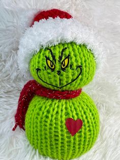 a green knitted christmas ornament wearing a santa hat