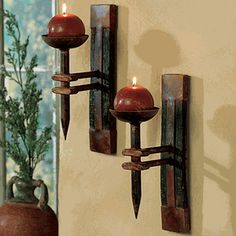 two candle holders are on the wall next to a vase with a plant in it