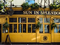 a yellow building with sun in the window and plants growing on it's side