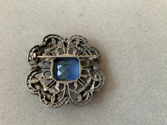 Beautiful blue stone brings brilliance to this old brooch. It measures 1.75 inches in width and length. Antique, and so pretty. Great gift for Mother's Day! Formal Blue Gemstone Brooch, Formal Blue Gemstone Brooches, Elegant Blue Gemstone Brooch, Elegant Blue Gemstone Brooches, Antique Blue Jewelry With Brooch, Vintage Gemstone Brooches For Formal Occasions, Vintage Blue Brooches For Jewelry Making, Blue Gemstone Brooch For Anniversary, Blue Gemstone Brooches For Anniversary