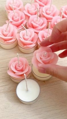 pink roses are placed in small cupcakes on a wooden table with white candles