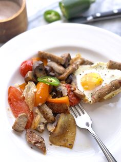 a white plate topped with meat and veggies next to a knife and fork