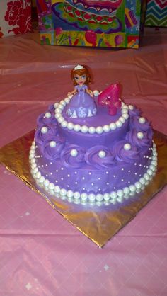 there is a purple cake with white frosting on the top and princess figurines