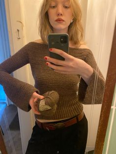 a woman is taking a selfie in the mirror with her cell phone while wearing a brown sweater