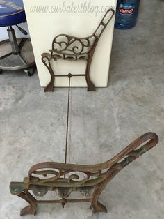 an old iron bench sitting on the floor next to a white wall and blue stool