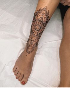 a woman's foot with a flower tattoo on her left leg and an intricate design