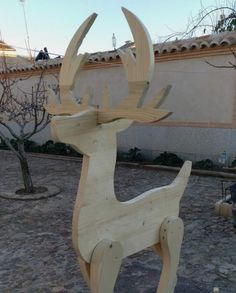 a wooden deer statue sitting on top of a stone ground