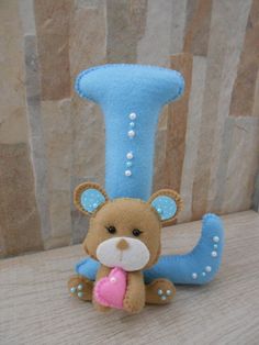 a teddy bear with a pink heart in its mouth sitting next to a blue letter