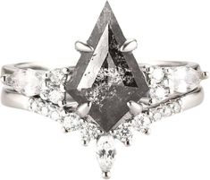 a white gold ring with an unusual shaped black diamond surrounded by smaller diamonds and cutouts