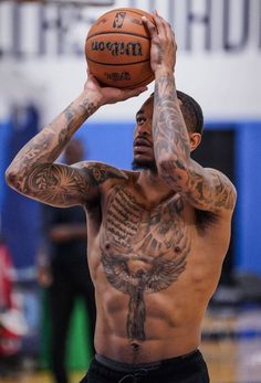 a shirtless man holding a basketball up to his face