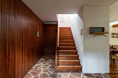 there is a wooden staircase leading up to the dining room and living room in this house