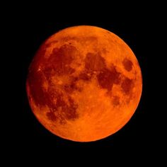 an orange full moon is seen in the dark sky