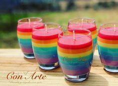 four colorful candles sitting on top of a wooden table