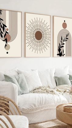 three art prints hanging on the wall above a white couch in a room with wicker chairs