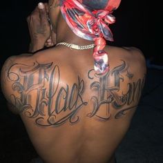 the back of a man with tattoos on his upper and lower back, wearing a bandana