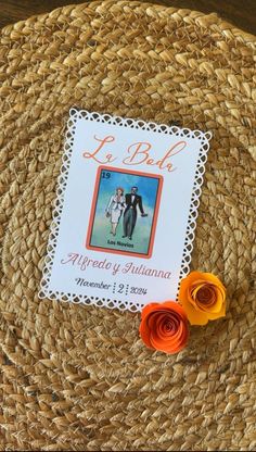 an orange rose sitting on top of a straw hat with the label for a book