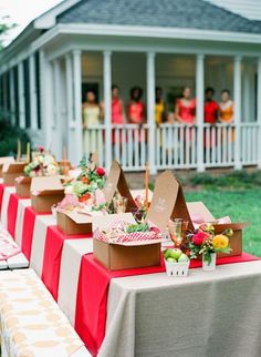 there are many boxes on the table with food and drinks in front of people standing behind them