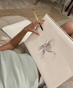 a person laying on the ground with a pencil in their hand and drawing something else