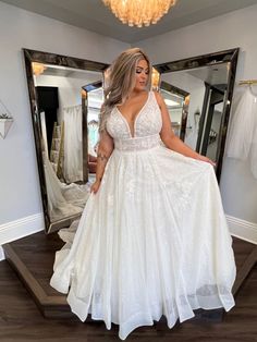 a woman standing in front of a mirror wearing a white dress