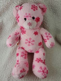 a pink teddy bear sitting on top of a bed