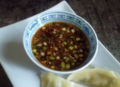 a bowl of soup and two dumplings on a plate