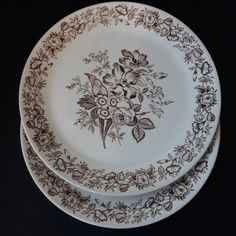 three brown and white plates sitting on top of each other in front of a black background