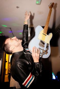 a man is holding his guitar up in the air