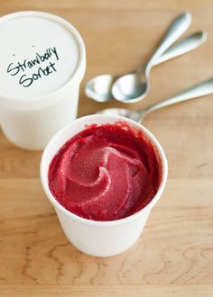 two cups filled with red liquid next to spoons