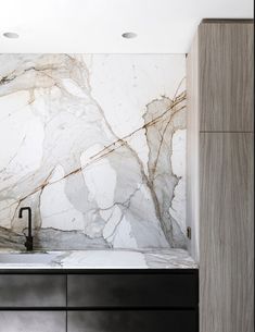 a kitchen with marble counter tops and black cabinetry, along with a sink in the middle