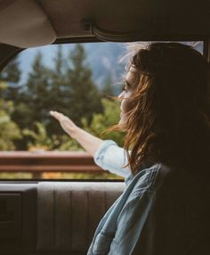 a woman sitting in the back seat of a car pointing at something out the window